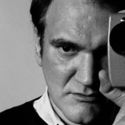 Quentin Tarantino looking through a handheld camera viewfinder.