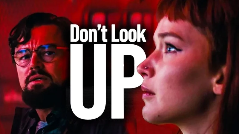 Red-colored poster photo for the movie Don't Look Up, featuring Leonardo DiCaprio as Randall Mindy and Jennifer Lawrence as Kate Dibiasky, with the text "Don't Look Up" prominently displayed.