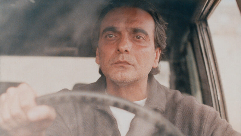 Homayoun Ershadi as Mr. Badii in Taste of Cherry, portrayed in a contemplative state while driving.