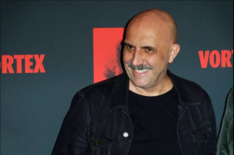 Gaspar Noé standing in front of the movie script for Vortex, with a smile on his face.
