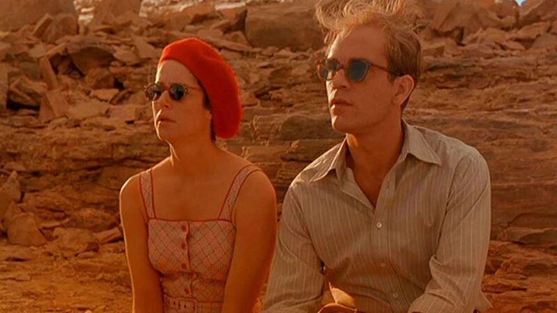 Debra Winger as Kit and John Malkovich as Port from The Sheltering Sky, seated with glasses adorning their eyes.