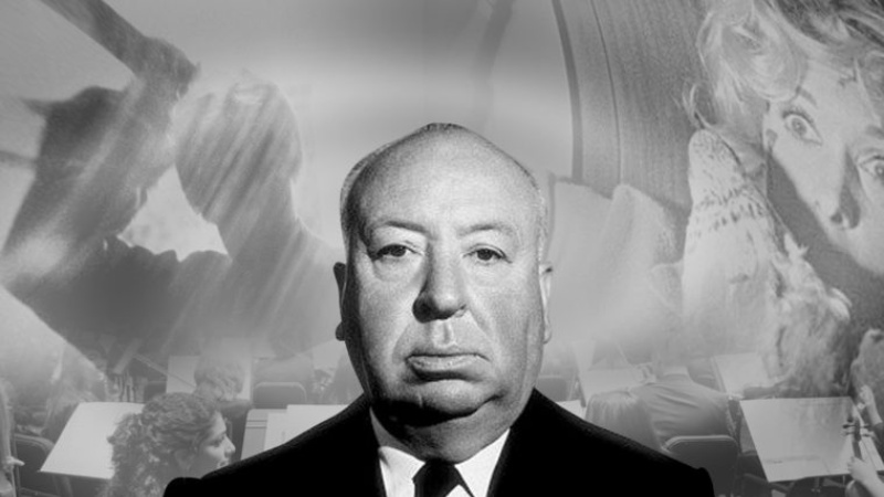 Alfred Hitchcock standing in front of movie posters of his films