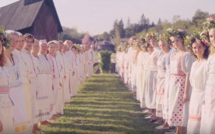 Members of the sect in white clothes smile and greet visitors at the Midsommar Ättestupa Ritual.