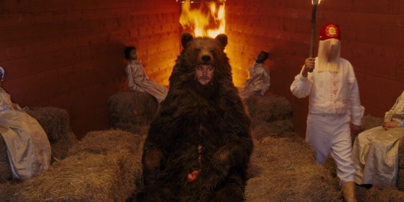 A man in a bear suit sits unaware that he will soon be burned.