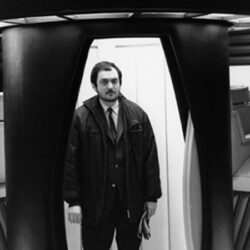 A black and white photograph of film director Stanley Kubrick standing on the set of the movie "2001: A Space Odyssey"