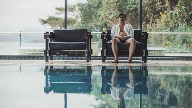 A scene from the movie "The Lobster" featuring the character David sitting by a swimming pool.