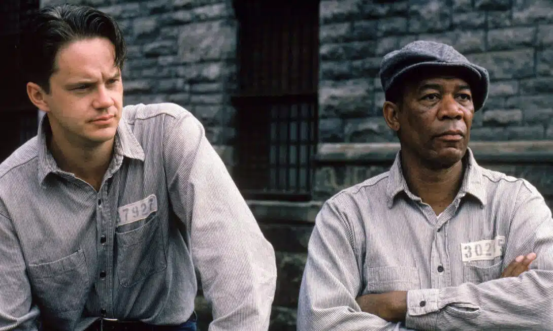 Tim Robbins as Andy Dufresne and Morgan Freeman as Ellis Boyd 'Red' Redding from The Shawshank Redemption, deep in thought. Red has his hands folded.
