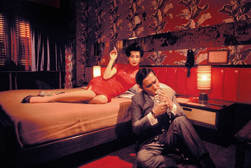 Su looks effortlessly glamorous in this still from "In The Mood For Love", lying on the bed with a cigarette in hand, while Chow prepares to smoke on the floor beside her.