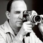 Ingmar Bergman peeks through a camera's viewfinder, with one eye closed and the other open.