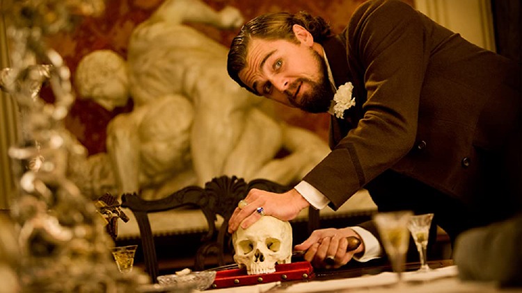 Calvin Candie (Leonardo DiCaprio) from the movie Django Unchained points a knife at the skull statue.