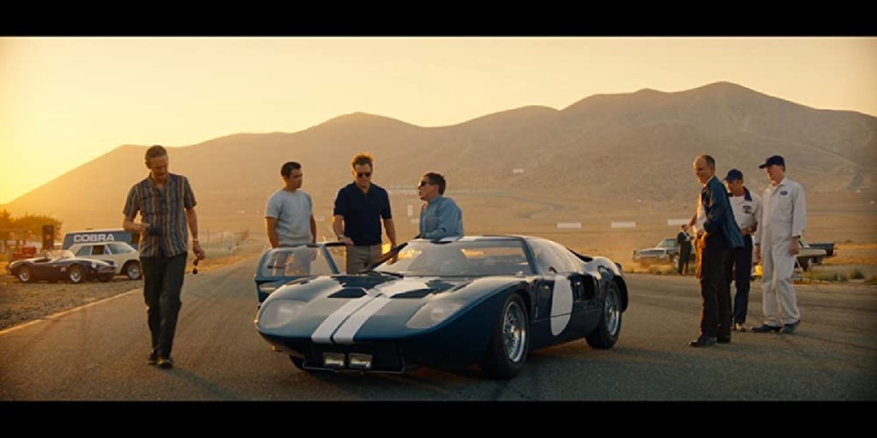 A car silhouetted against a breathtaking sunset, symbolizing community and the spirit of camaraderie depicted in the movie Ford v Ferrari.