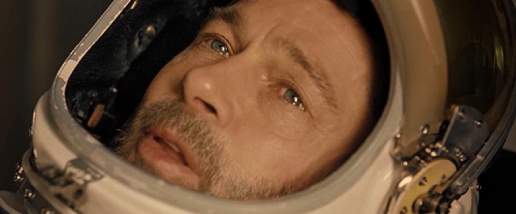 Roy McBride (played by Brad Pitt) from the movie "Ad Astra" appears teary-eyed and vulnerable in his space suit, conveying a sense of helplessness.