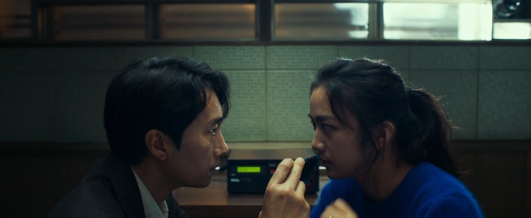 Jang Hae-joon (played by Park Hae-il) and Song Seo-rae (played by Tang Wei) from the movie "Decision to Leave" share a deeply contemplative gaze.