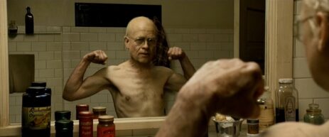 Brad Pitt as Benjamin Button posing in front of a mirror, showcasing his muscular biceps.