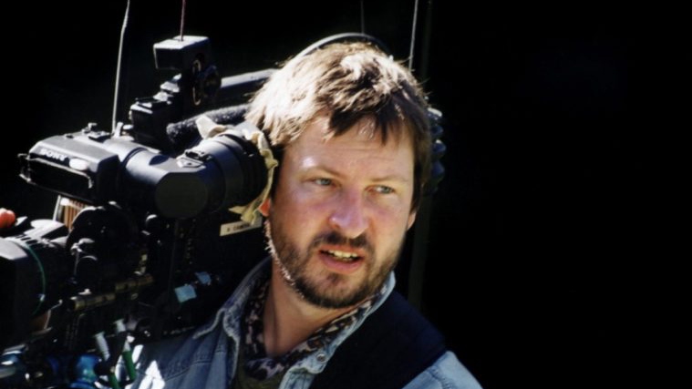 Young Lars von Trier with a camera over his shoulder, focused on something beside him.