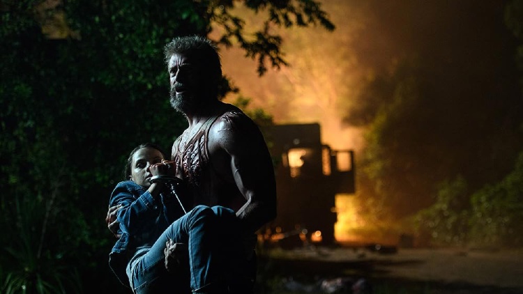 Hugh Jackman as Logan heroically cradles Laura (Dafne Keen) in his arms, saving her.