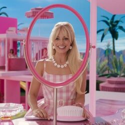 Barbie (2023) Review: Modern Feminist Parody! Margot Robbie as Barbie smiling at her reflection in an empty mirror in a scene from the movie.