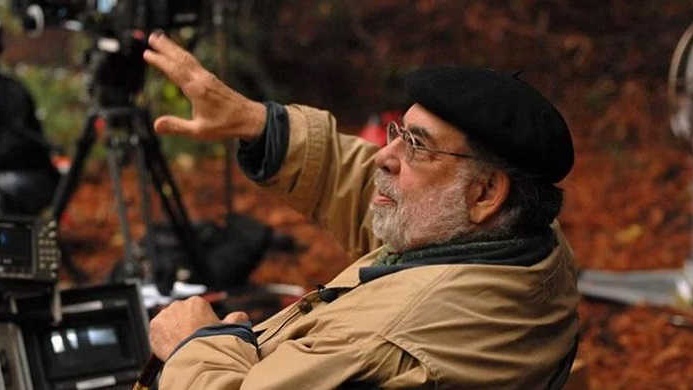 An elderly Francis Ford Coppola seated in the director's chair, actively overseeing a film production.