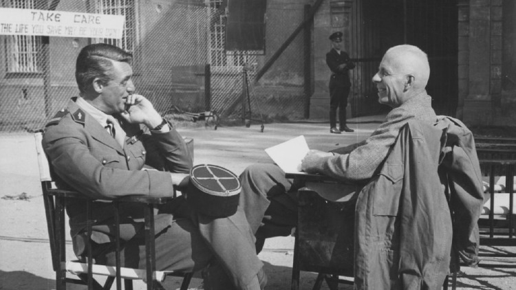 Cary Grant and Howard Hawks share a jovial moment, seated in chairs and laughing on the set of 'I Was a Male War Bride' (1949).