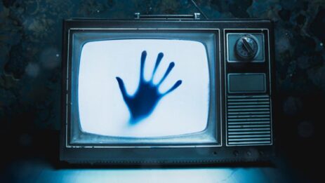 A chilling scene with a weathered television featuring a mysterious hand, setting the stage for a spine-tingling horror movie.