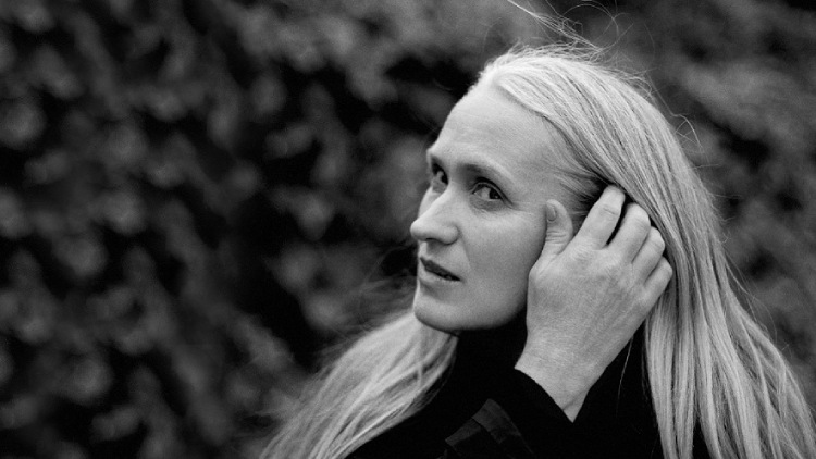 Jane Campion gracefully tucks her hair behind her ear, displaying a simple yet elegant gesture.