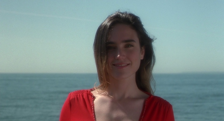 Jennifer Connelly as Marion Silver in the movie "Requiem for a Dream" radiates beauty in her red dress, with a captivating smile.