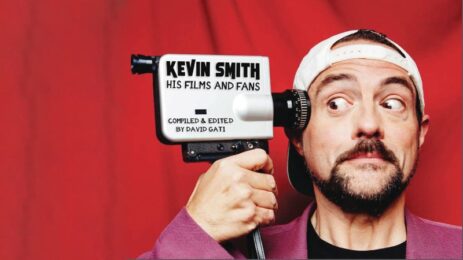 Kevin Smith striking a pose with a movie, pointing it to his head mimicking a gun.