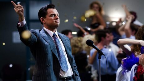 Leonardo DiCaprio as Jordan Belfort in a scene from "The Wolf of Wall Street," raising his hand in an honorable gesture.