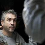 10 Signature Elements of Alfonso Cuarón's Filmmaking Style! Director Alfonso Cuarón on the set of the movie 'Gravity,' raising his hands in a moment of creative direction.
