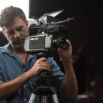 10 Signature Elements of Paul Thomas Anderson's Filmmaking Style! Director Paul Thomas Anderson adjusts the camera on a tripod, ensuring the precise shot in the filmmaking process.