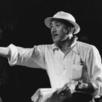 10 Signature Elements of Yasujirō Ozu's Filmmaking Style! Director Yasujirō Ozu on the film set, wearing a hat, holding a script in hand, as he points and directs a movie scene.