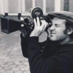 10 Signature Elements of Miloš Forman's Filmmaking Style! Milos Forman, the acclaimed director, gazes through the viewfinder of his handheld camera, framing a shot with precision.