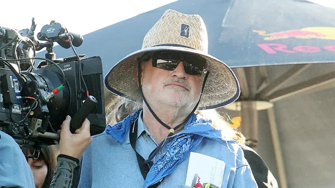 Terrence Malick sporting a hat and sunglasses at a Red Bull event, exuding a cool and composed vibe.