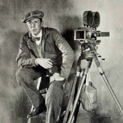 10 Signature Elements of F.W. Murnau’s Filmmaking Style! Image of a director at the F.W. Murnau film studio sitting near a camera mounted on a tripod, striking a pose.