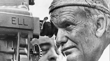 Close-up shot of director Sam Peckinpah looking through the camera's viewfinder, engaged in directing the film.