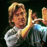 10 Signature Elements of Paul Verhoeven’s Filmmaking Style! Paul Verhoeven on a film set, directing a scene by gesturing with his hand to indicate the movie's scene.