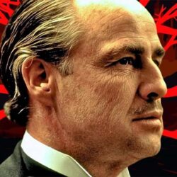 Close-up of actor Marlon Brando in his role as Vito Corleone from The Godfather, against a red background.
