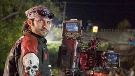 Director Robert Rodriguez on the film set, dressed in biker clothes, buff , sunglasses on his head, striking a pose behind the camera.