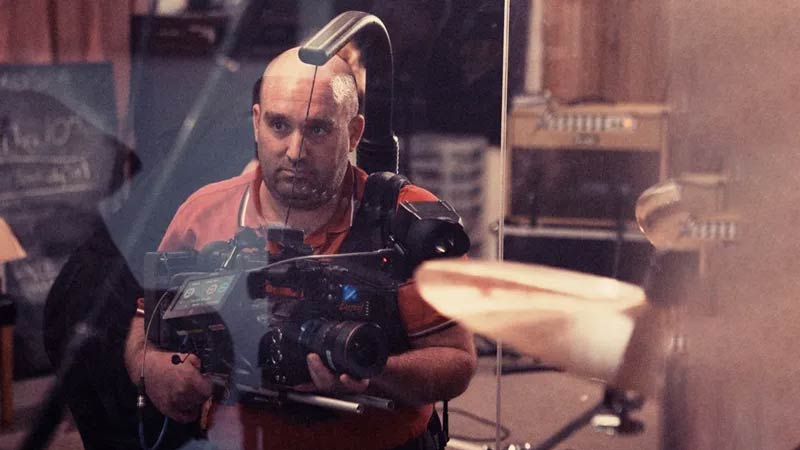 Director Shane Meadows on the film set, holding a camera in hand and actively directing a movie scene.